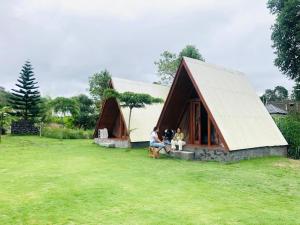 two people sitting outside of a small house at Segara Healing Bali Glamping With Hot Spring in Kubupenlokan