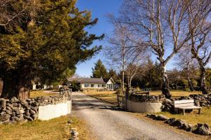 a road leading to a house with a fence and a bench at Tekapo1929 Lakefront Villa in Lake Tekapo