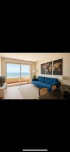 a living room with a blue couch and a view of the ocean at Vue sublime mer in Canet-en-Roussillon +7 photos