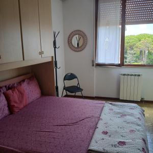 a bedroom with a pink bed and a chair in it at Grande e luminoso appartamento in Lido di Classe