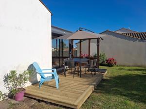 eine Holzterrasse mit Tisch und Sonnenschirm in der Unterkunft Maison de vacances 6 personnes in Saint-Hilaire-de-Riez