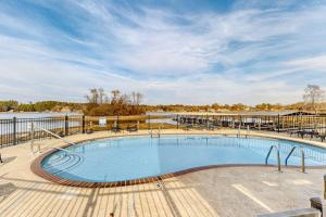 a large swimming pool on a deck next to a body of water at Lakefront Townhouse with Lake, Pool & Tennis in Red Oak
