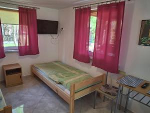 a small bedroom with red curtains and a bed at Domki u Ani in Okuninka
