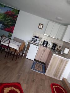 LipniţaにあるCăsuța buniciiの白いキャビネットとテーブル付きのキッチン、ダイニングルーム付きのキッチン