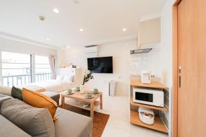 Una sala de estar con un sofá y un televisor. en SAIEI HOTEl 201, en Tokio