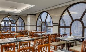 a restaurant with tables and chairs and windows at Emaar Taiba Hotel in Medina
