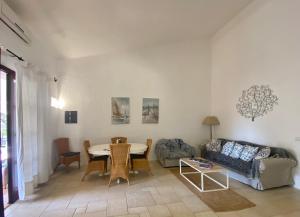 un soggiorno con un tavolo e un divano di Villa Meigama - Porto Giunco a Notteri