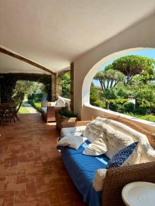 una camera con letto e vista sul giardino di Villa Meigama - Porto Giunco a Notteri