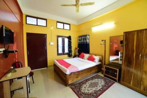 a bedroom with a bed and a desk and a tv at Hotel Alohi Ghar in Jorhat