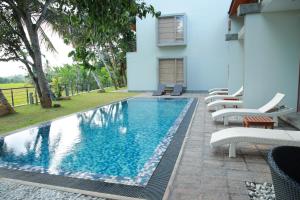 a swimming pool in front of a house with lounge chairs at ONA Garden Villa in Galgamuwa
