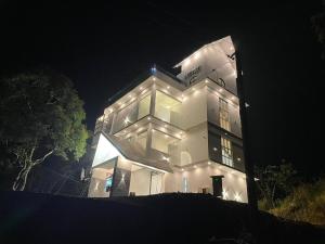 a large white building with lights on it at night at The Fortunara Crown Munnar in Munnar