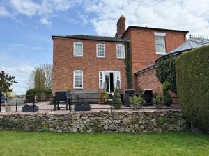 a brick house with chairs and a stone wall at Garden cottage at The Glebe in Bayton