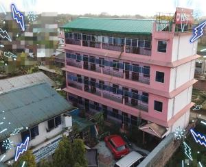 a pink building with a car parked in front of it at Hotel Alohi Ghar in Jorhat