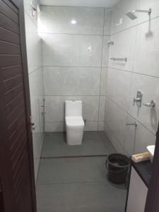 a white bathroom with a toilet and a shower at The Fortunara Crown Munnar in Munnar
