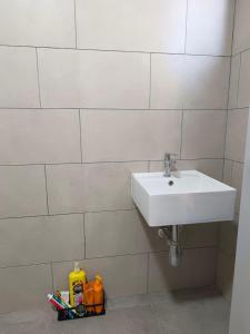 La salle de bains est pourvue d'un lavabo blanc et d'un mur en carrelage blanc. dans l'établissement Sakura Putrajaya Homestay Mus lim Only, à Putrajaya