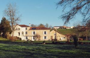 a large white house on a grassy field at Moulin de Saza in Le Vigeant