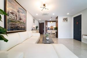 a living room with a white couch and a painting on the wall at The Silver Vinh Hoi Apartment in Ho Chi Minh City