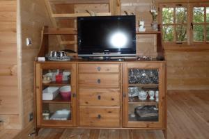 a television on a wooden entertainment center in a cabin at L'Arche en Brenne in Neuillay-les-Bois