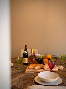 a wooden table with bottles of wine and bread and wine glasses at Le Col Getaway Virage 3 in Le Bourg-dʼOisans