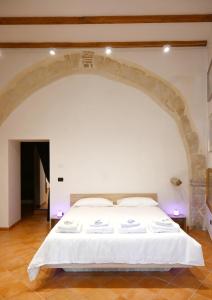 a large white bed in a room with an arch at La Corte dell'Annunziata - Casa in centro con giardino in Sulmona +28 photos