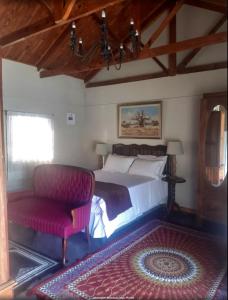 a bedroom with a bed and a red chair at Die Waenhuis in Parys