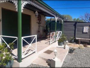 a patio with a green building and a fence at Die Waenhuis in Parys +7 photos