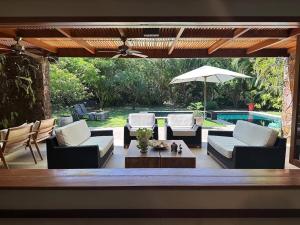 a patio with couches and a table and an umbrella at Canto das Pedras House in Mata de Sao Joao
