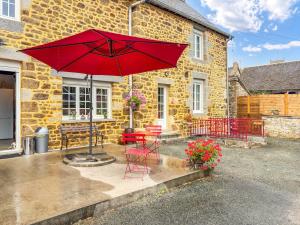 a patio with a red umbrella and a table and chairs at L'Écrin Normand in La Ferté-Macé