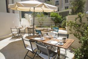 a patio with tables and chairs with an umbrella at Cristal Hôtel & Spa in Cannes