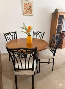 un tavolo in legno con quattro sedie e un vaso con fiori di Apto El Pinillo Confort y Sol a Torremolinos