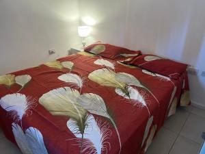 a bed with a red comforter with leaves on it at Depa pleno centro Santa Fe in Santa Fe