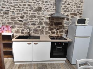 a kitchen with white cabinets and a stone wall at Les petits gites Ernée in Ernée