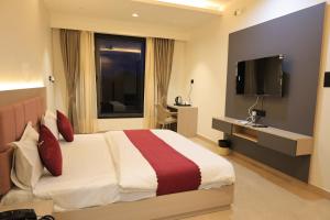 een hotelkamer met een bed en een flatscreen-tv bij The Basil Hotel in Udaipur