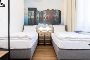 two beds in a room with a painting on the wall at Renatus Apartments in Eschau