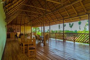 ein Esszimmer mit einem Tisch und Stühlen auf einem Holzboden in der Unterkunft Nzoghu Heritage Safari Camp in Kasese