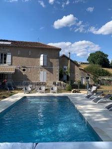a swimming pool with chairs and a house at Moulin de Saza in Le Vigeant