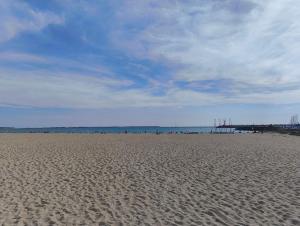 una playa de arena con gente a lo lejos en maison a côté du port et du centre, en La Turballe