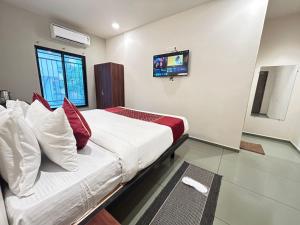 a bedroom with a bed with a tv on the wall at SwagStay Hotel Riviera Grand, Nagpur in Nagpur