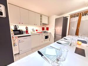 una cucina con armadi bianchi e un tavolo con bicchieri di Le Repaire du Lion - Quadruplex - 10 voyageurs a Belfort Altre 27 foto