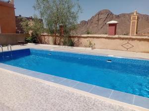 a swimming pool with blue water in front of a building at Auberge Restaurant TISSILI " Oasis de Fint" in Fint
