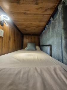 a bed in a room with a wooden ceiling at Hostel Navi Osh in Osh