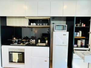 a kitchen with white cabinets and a white refrigerator at Comfy Unit in front of Crown with Free Parking in Melbourne +5 photos