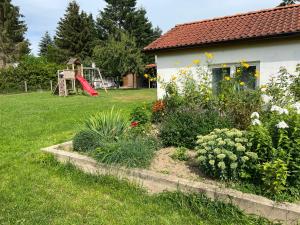 een achtertuin met een tuin met bloemen en een speeltuin bij Ferienwohnungen Wiedemann WE 1 in Mellenthin