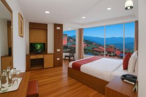 a hotel room with a bed and a large window at Central Heritage Resort & Spa Formerly Fortune ITC Resort in Darjeeling