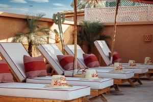 una fila di sedie a sdraio con cuscini su un patio di Riad Le Terracotta a Marrakech