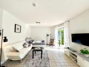 a white living room with a couch and a tv at Kleines Idyll, Ruhig & erholsam - Peter M22 - Frankenwald Apartments in Stadtsteinach