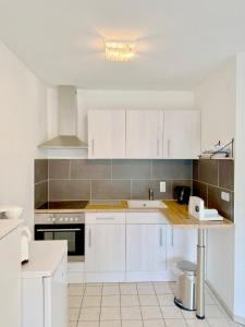 a white kitchen with white cabinets and a counter at Kleines Idyll, Ruhig & erholsam - Peter M22 - Frankenwald Apartments in Stadtsteinach