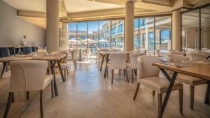 a restaurant with wooden tables and chairs and windows at Selyria Resort in Tsilivi
