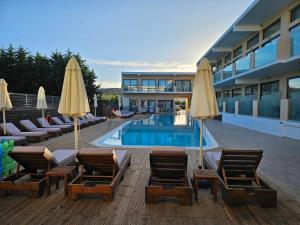 a hotel with chairs and umbrellas and a swimming pool at Selyria Resort in Tsilivi