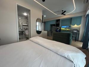 Un dormitorio con una gran cama blanca y una sala de estar. en UHomes Pune airport, en Pune